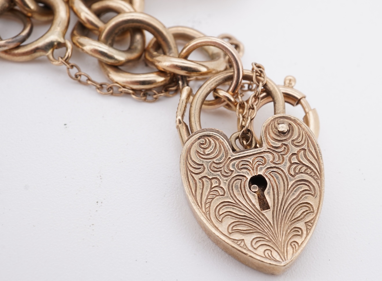 A 1970's 9ct gold curb link charm bracelet, with 9ct gold heart shaped clasp, hung with seven assorted gold or gilt metal mounted charms including six chalcedony set fob seals, gross weight 73 grams.